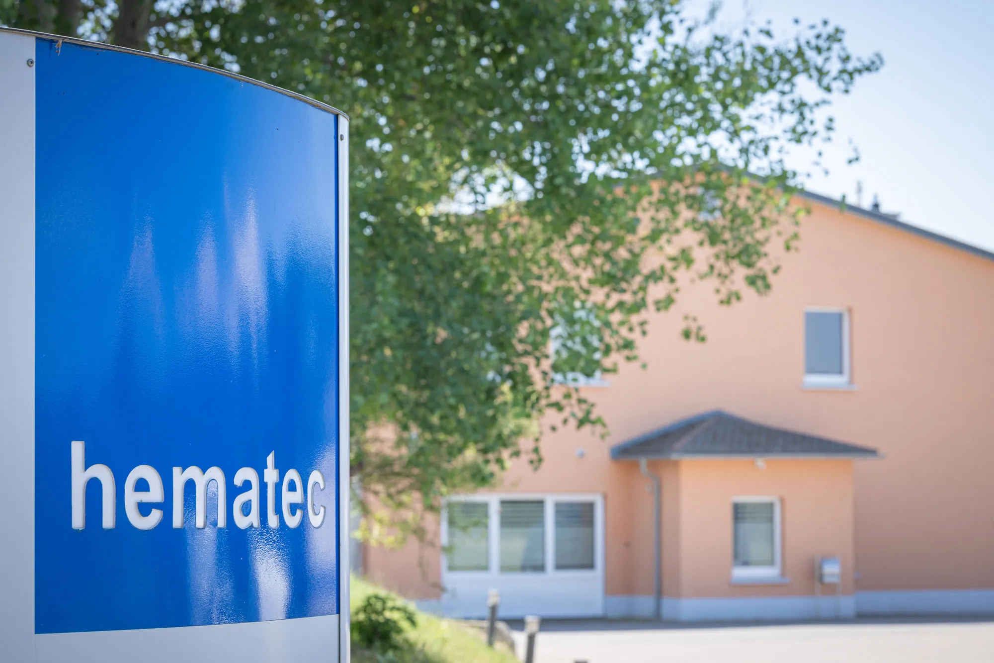 hematec Schild mit Gebäude im Hintergrund